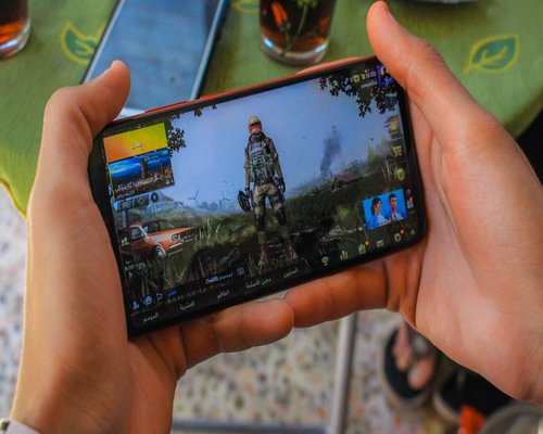Player holding a smartphone with a colourful fictional CROWN mobile game on screen